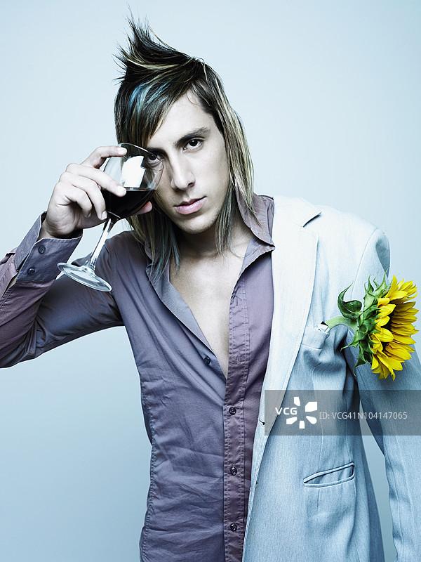 年轻男子用红酒杯遮住眼睛的肖像图片素材