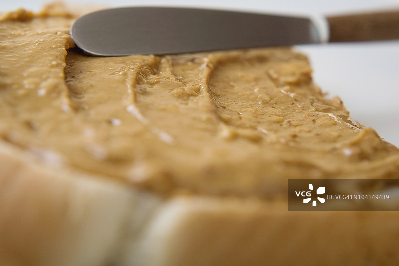 刀在面包片上涂抹花生酱的特写镜头图片素材