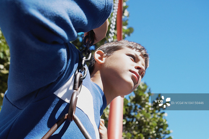 低角度视图的少年在秋千上图片素材