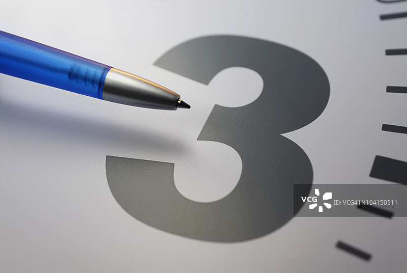圆珠笔特写指向时钟上的数字三图片素材