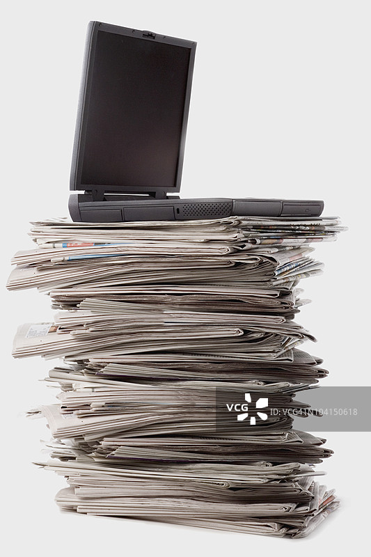 笔记本电脑放在一堆报纸上的特写镜头图片素材