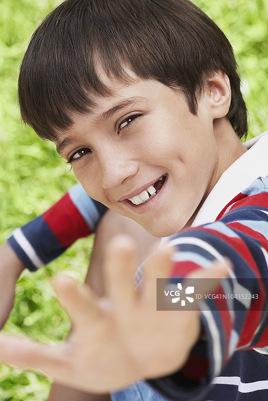 一个男孩微笑着伸出手的肖像图片素材