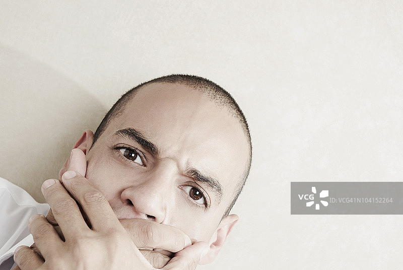 一位用手捂住嘴的年轻男人的肖像图片素材