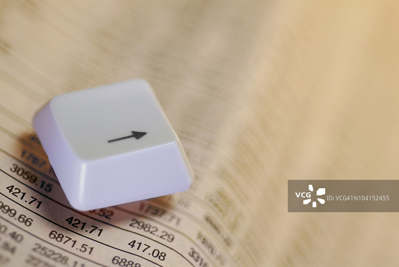 计算机键盘上的按钮特写，旁边是一份财经报纸图片素材