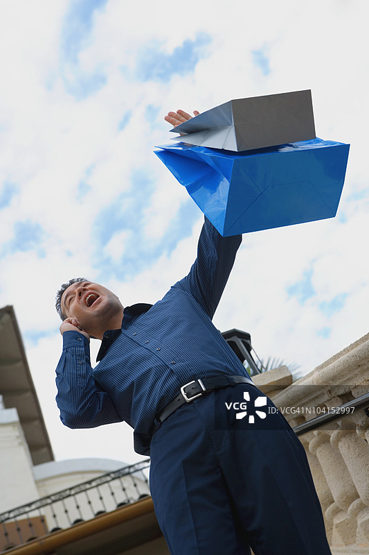低角度视图的中年男子站在台阶上，手里提着购物袋图片素材