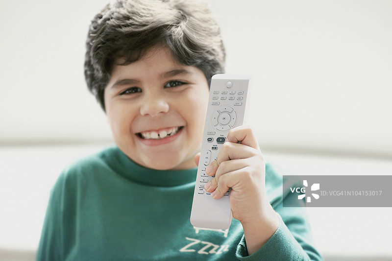 一个男孩微笑着拿着遥控器的特写镜头图片素材