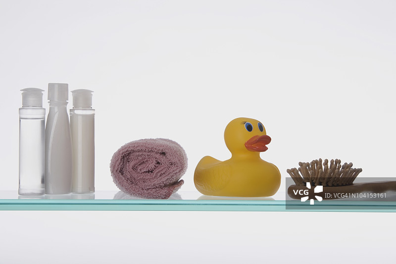 玻璃架子上带有洗漱用品的橡胶鸭特写图片素材