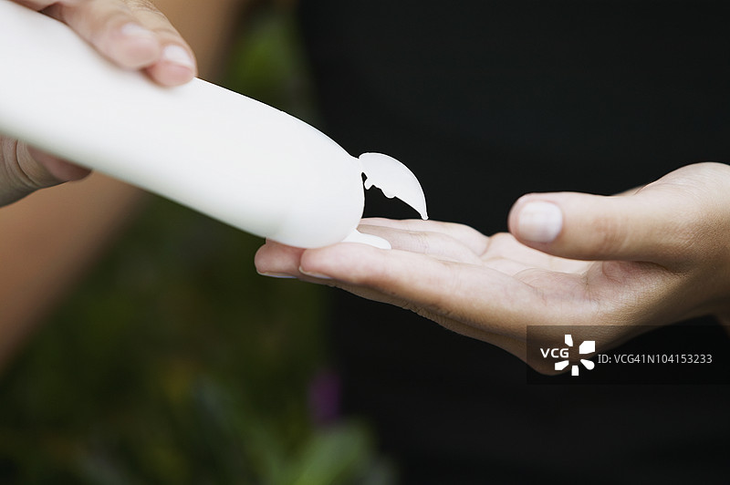 一个人手部特写，挤压保湿霜瓶子图片素材