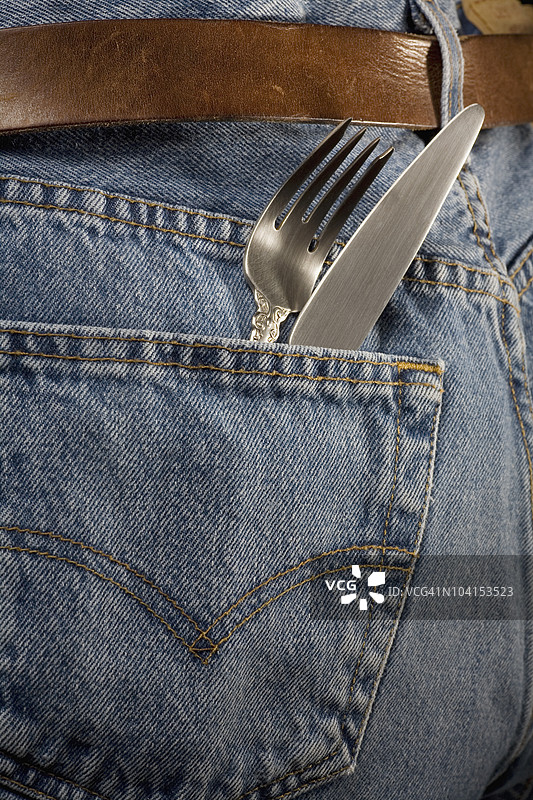 一把厨房刀和一把叉子放在一条牛仔裤的口袋里特写镜头图片素材