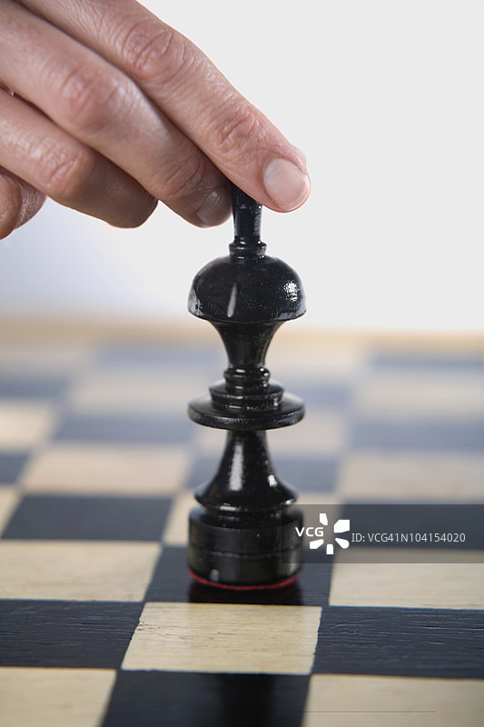 一个人的手指特写，握着一个棋子图片素材