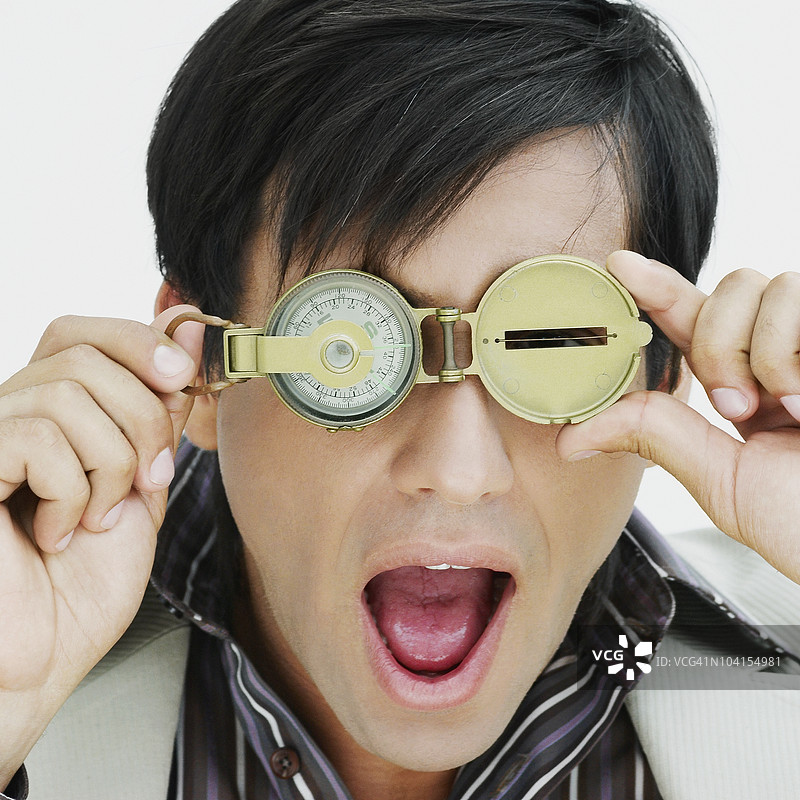 年轻男子透过指南针观察的特写镜头图片素材