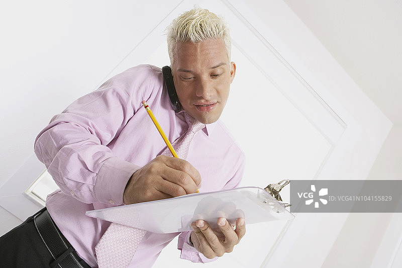 用手机讲话并在写字板上书写的商人图片素材