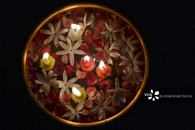 黄铜碗/烛台上漂浮的玫瑰花瓣、星茉莉花和蜡烛 - 排灯节图片素材