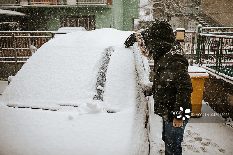 男人清理汽车上的积雪图片素材