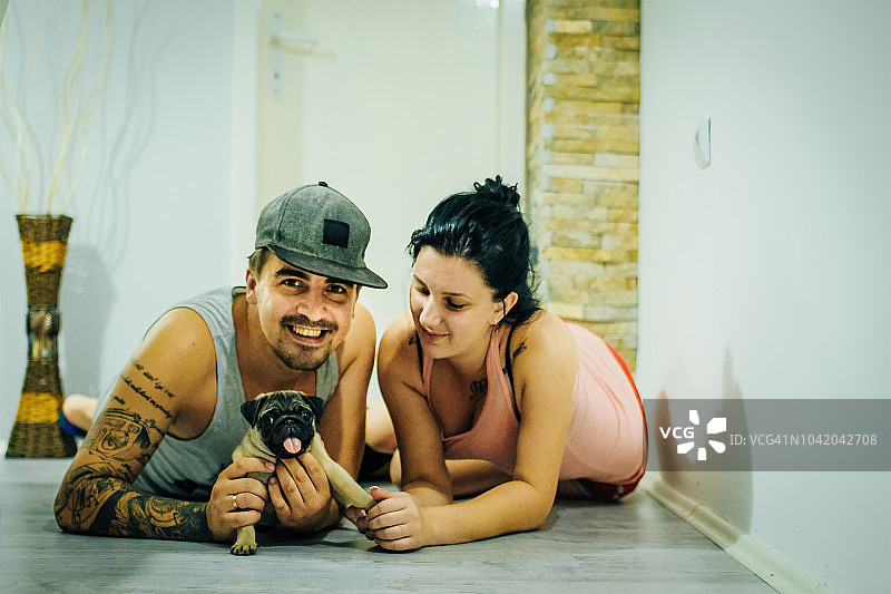 年轻夫妇和宠物狗在地板上放松图片素材