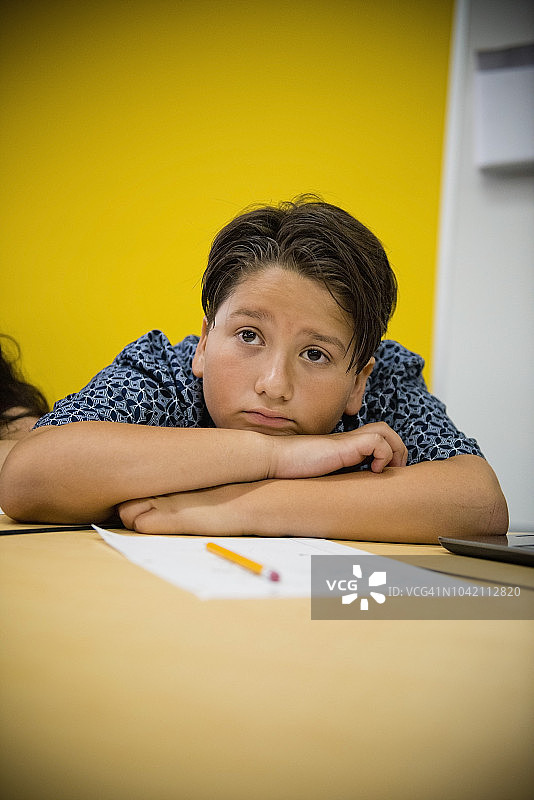 在现代城市特许学校课桌旁休息的青少年男孩图片素材