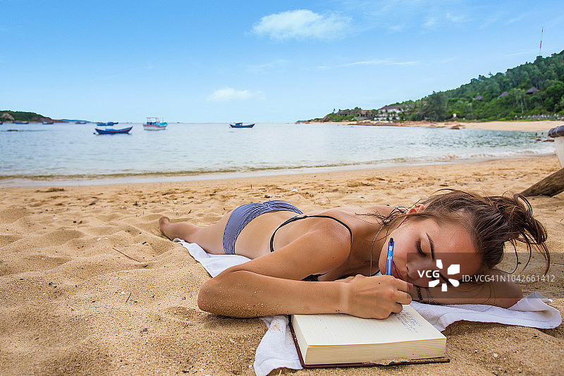 在白叶渔村海滩上写日记的女人图片素材