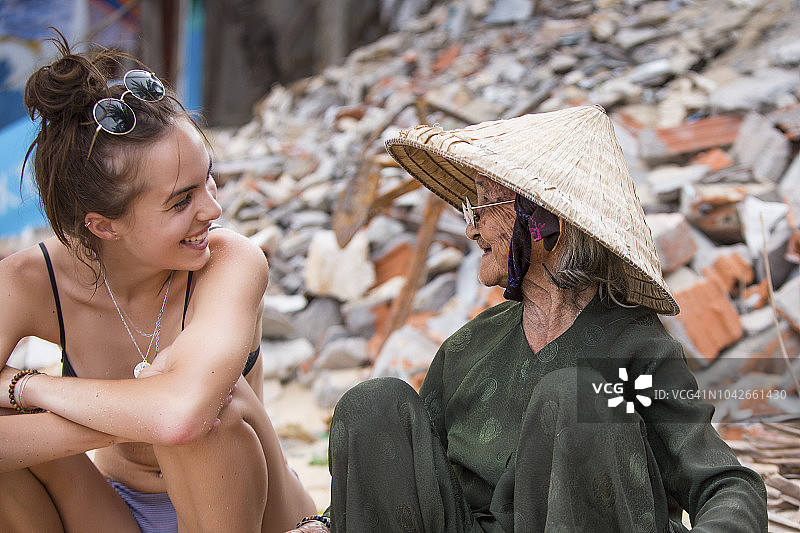 在Bai Xep村，年轻游客停下来与一位辛勤劳作的当地老妇人相遇并欢笑图片素材