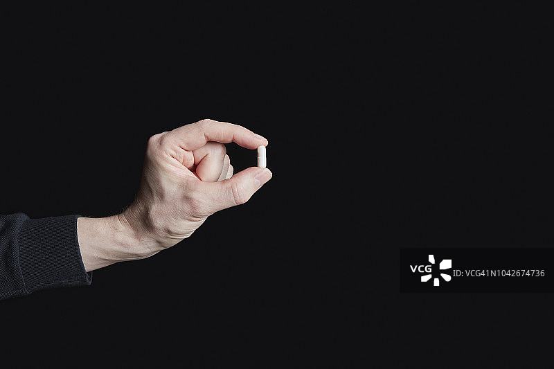 男人在黑色背景下拿着药丸图片素材