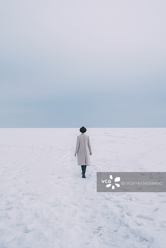 戴帽子、穿大衣在雪地里行走的女人图片素材
