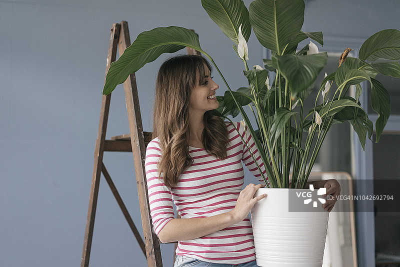 女人在新家中手持盆栽图片素材