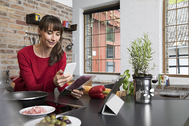 在厨房里用智能手机扫描产品的女人图片素材