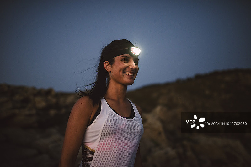 晚上戴着头灯的运动型女人图片素材