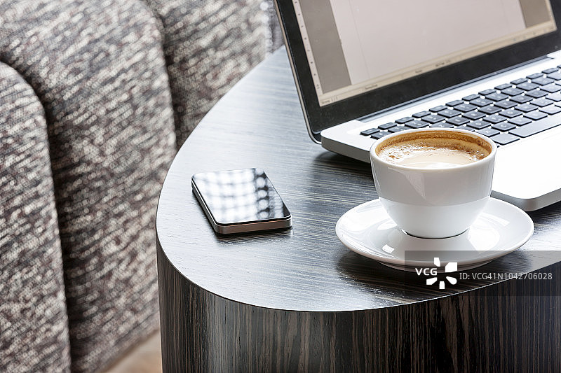 波兰华沙酒店休息区的笔记本电脑、智能手机和咖啡杯图片素材