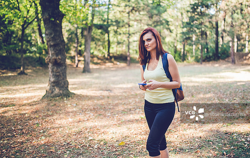 在森林中漫步时使用智能手机的女人图片素材