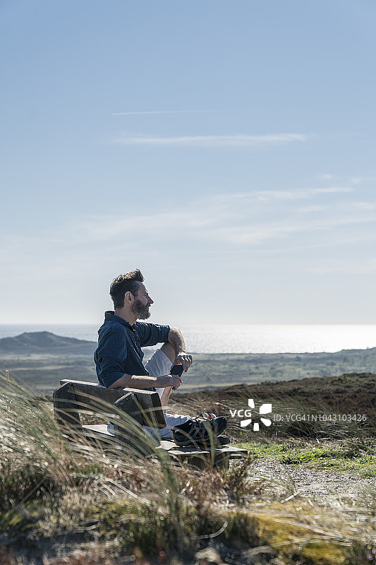男人坐在长椅上看海图片素材