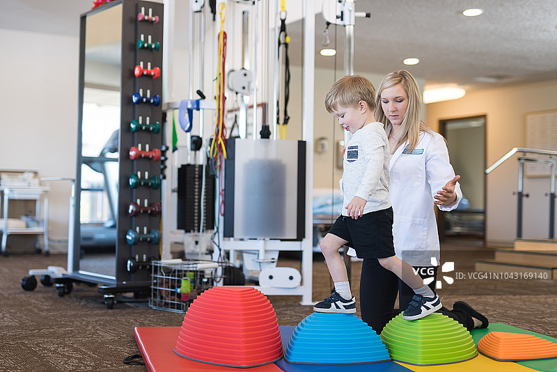 理疗师在诊所帮助年轻男孩图片素材