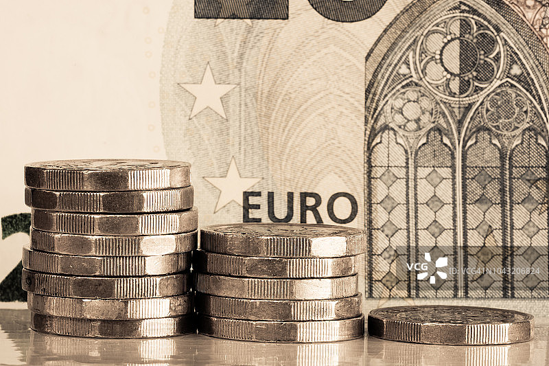 堆叠成三堆的1英镑硬币和20欧元纸币图片素材