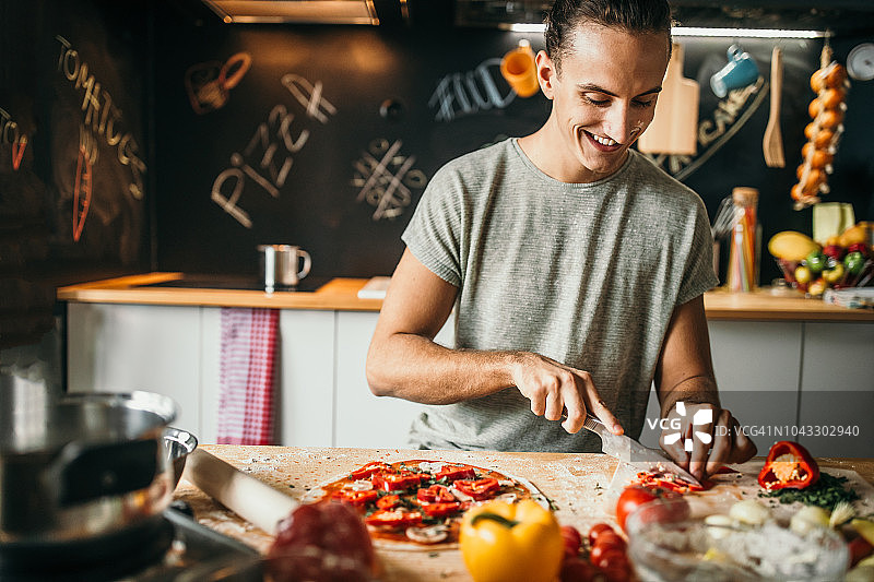 年轻男人在家准备披萨图片素材
