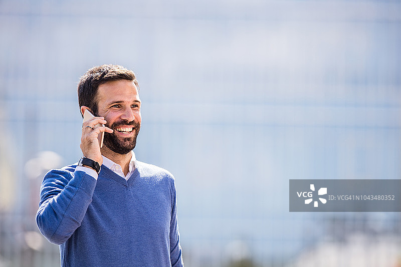 在城市里用智能手机与人交流的快乐商人图片素材