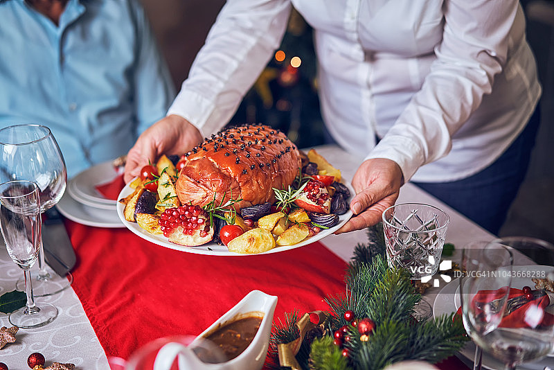 圣诞晚餐：蜜汁火腿、蔬菜、肉馅饼和蛋奶酒橙子甜点图片素材