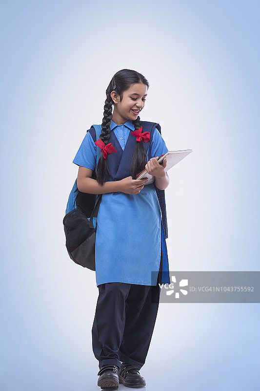 身穿校服、手拿书本和书包的乡村女孩图片素材