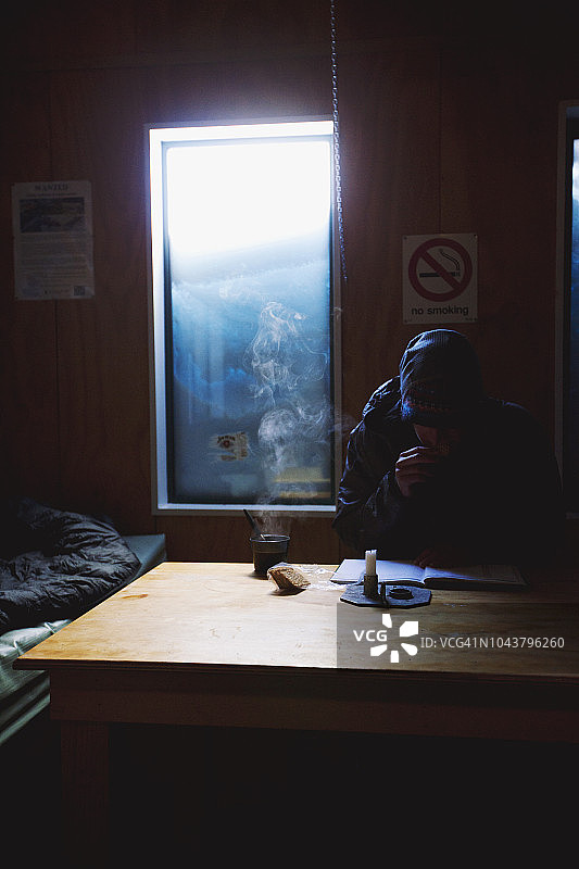 男人在新西兰南岛的桌旁喝着热茶读书图片素材