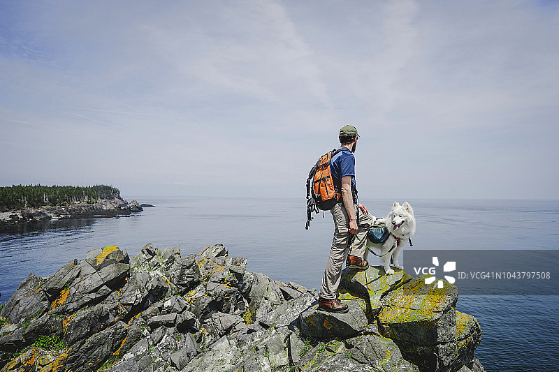 男人带狗沿着大西洋海岸徒步旅行图片素材