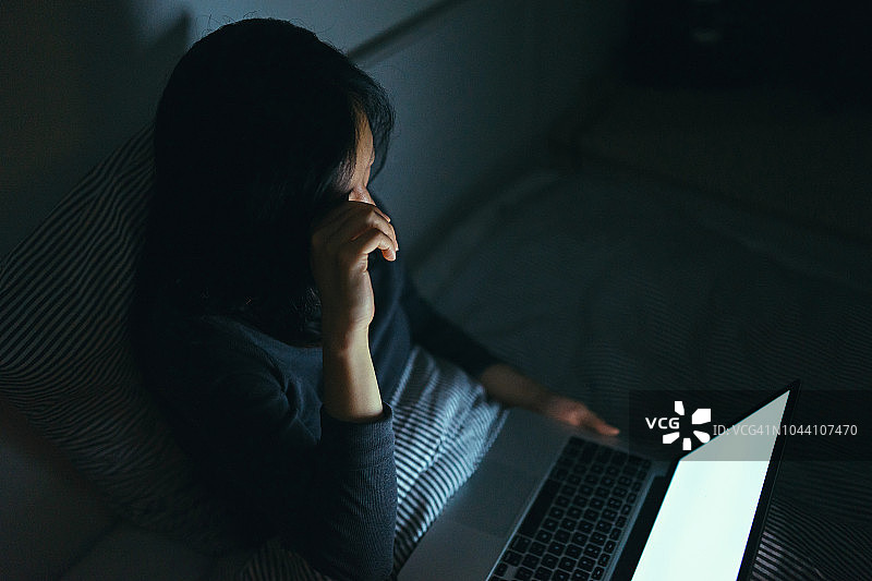 疲惫的女人在床上工作到深夜揉眼睛图片素材