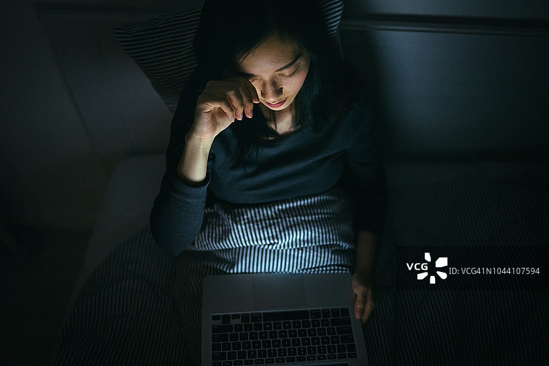 疲惫的女人在床上工作到深夜揉眼睛图片素材