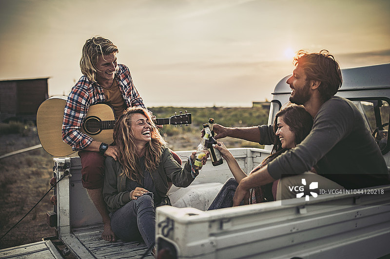 夕阳下皮卡车中幸福情侣举杯庆祝图片素材