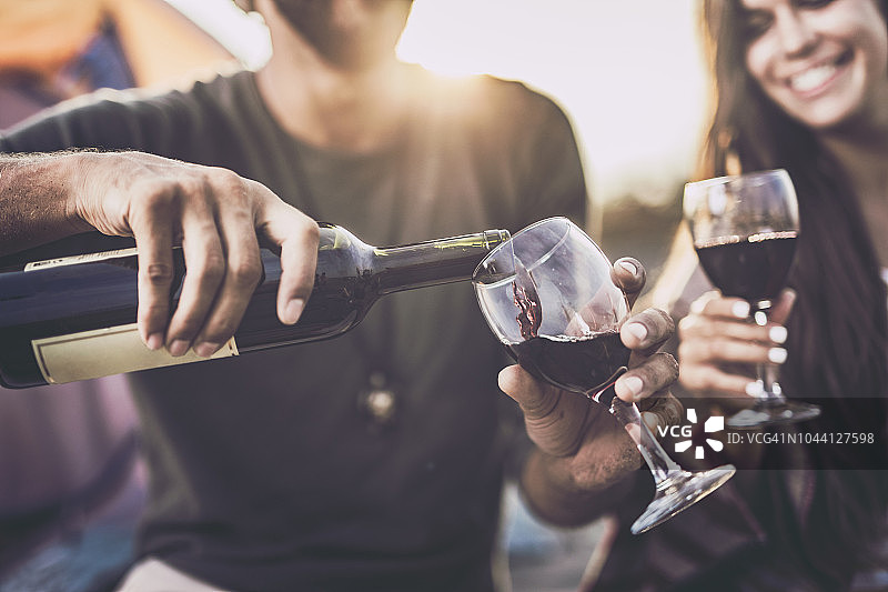 户外往玻璃杯里倒红酒特写图片素材