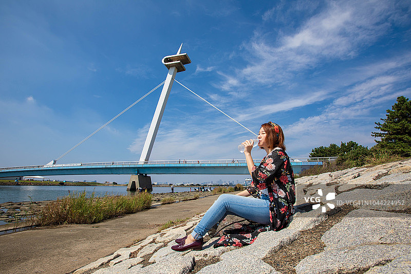 在海边喝水的年轻女人图片素材