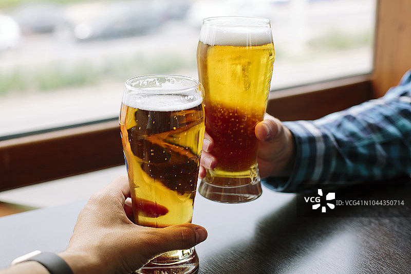 两个男人的手拿着啤酒杯的特写图片素材