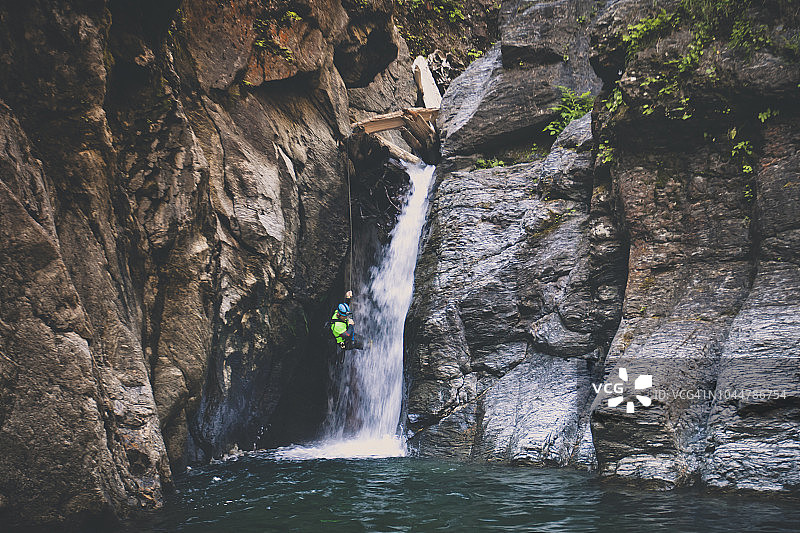 男子在加拿大不列颠哥伦比亚省迪诺溪的瀑布上绳降图片素材