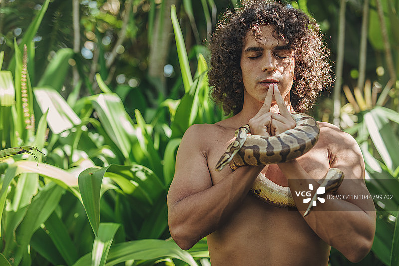 在森林里拿着蛇的年轻男人图片素材