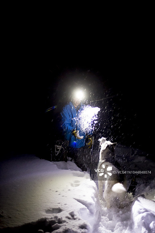 男子在爱达荷州和蒙大拿州边界的洛洛山口戴着头灯在夜间滑野雪。图片素材