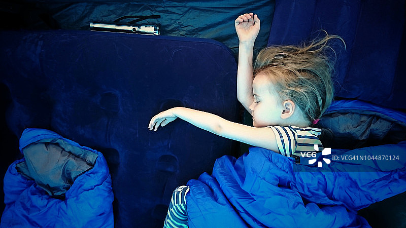 4至5岁女孩在帐篷里的睡袋中睡着了图片素材