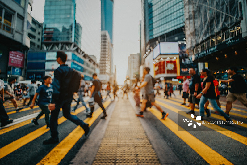 市中心区繁忙的通勤者穿过街道，背景是现代企业摩天大楼的散焦图像图片素材