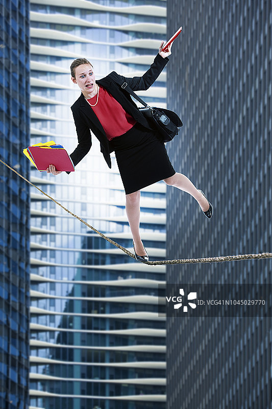 走在城市上空钢丝上的女商人图片素材